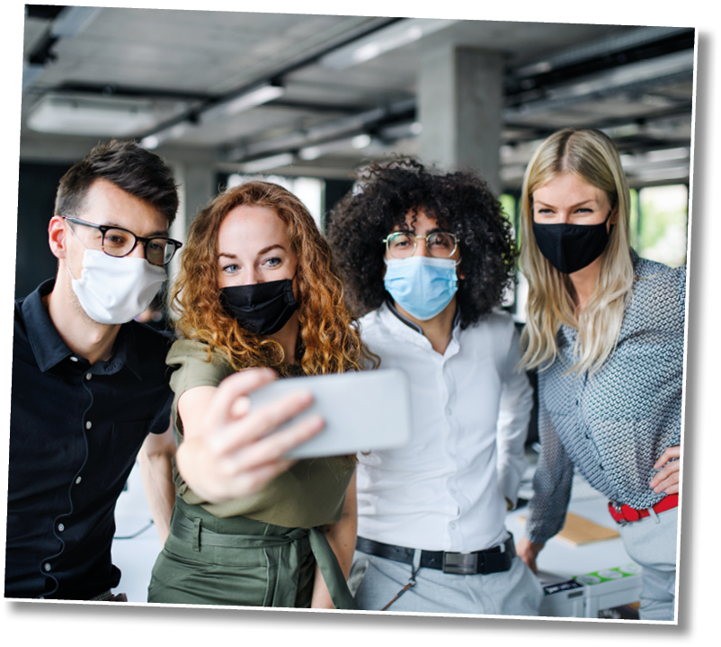 Young people with face masks back at work in office after lockdown, taking selfie 