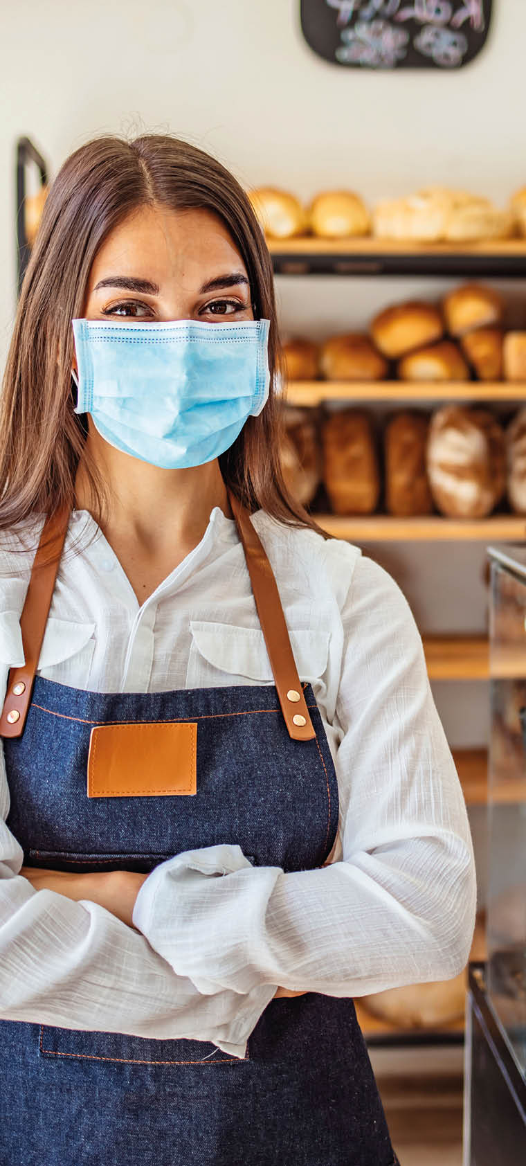 Woman working at a bakery wearing a facemask to avoid the coronavirus  COVID-19 lifestyle concepts  Day in the life of owners of bakery shop with the protocol against the Covid-19 in place  