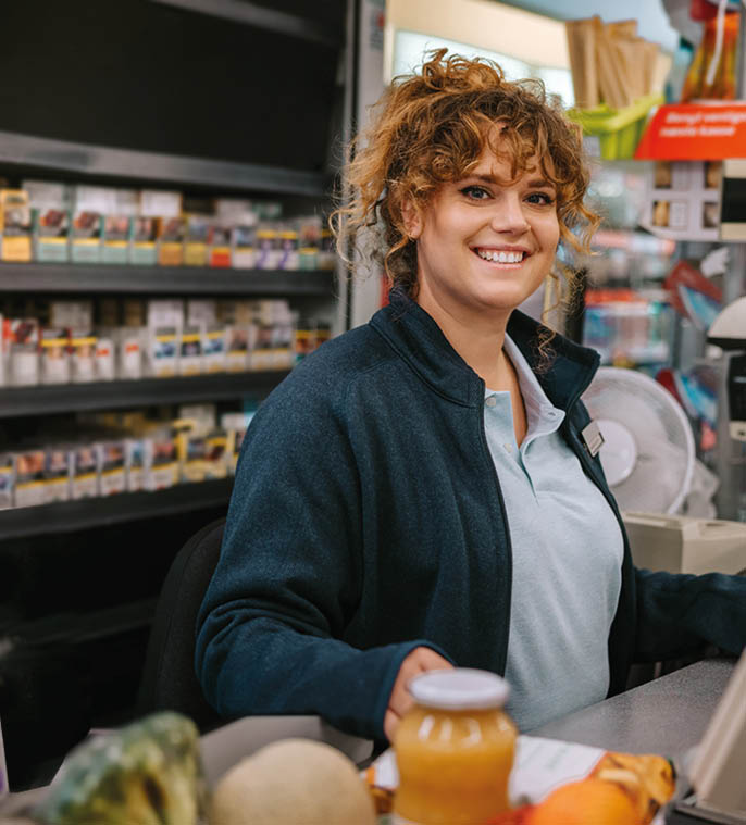 Portrait of a happy woman working at checkout counter smiling at camera  Supermarket employees working at cash register counter 