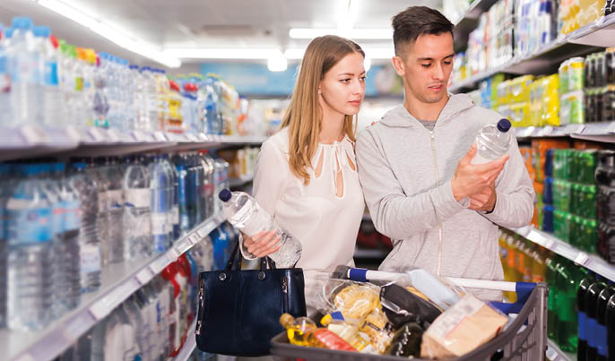 Adult woman and man buying still water in grocery section at supermarket