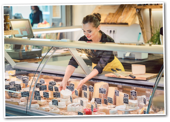 Shop clerk woman sorting cheese in the supermarket display to sell it