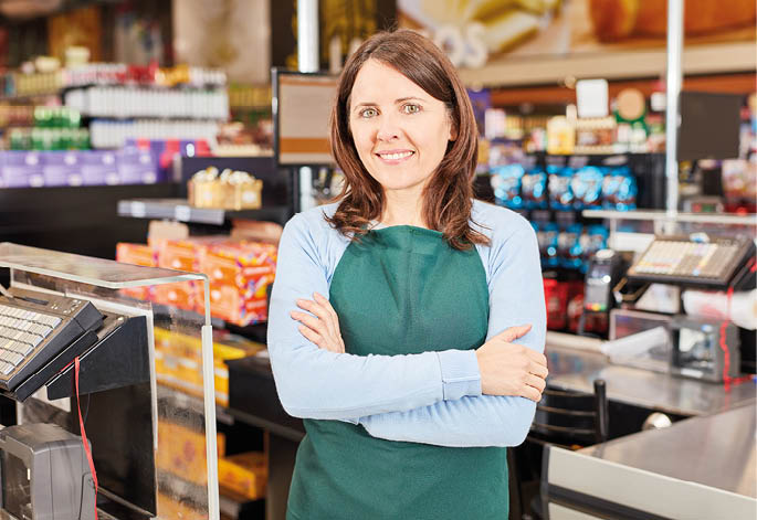 Young woman as a cashier or assistant in the supermarket with crossed arms