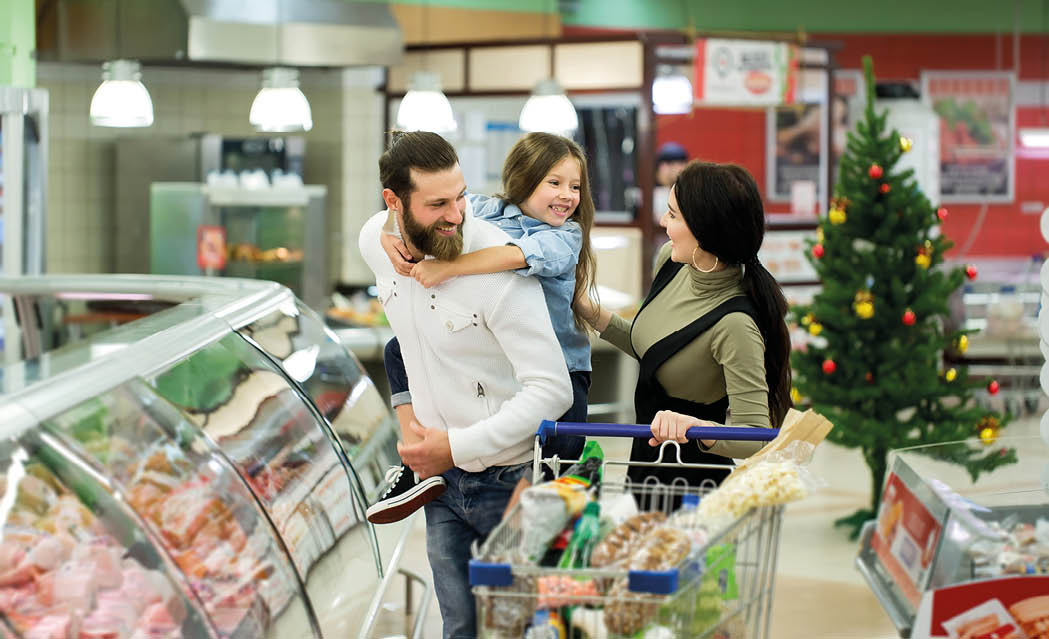 Young family with a little girl shopping in a large supermarket  Concept of a new year 