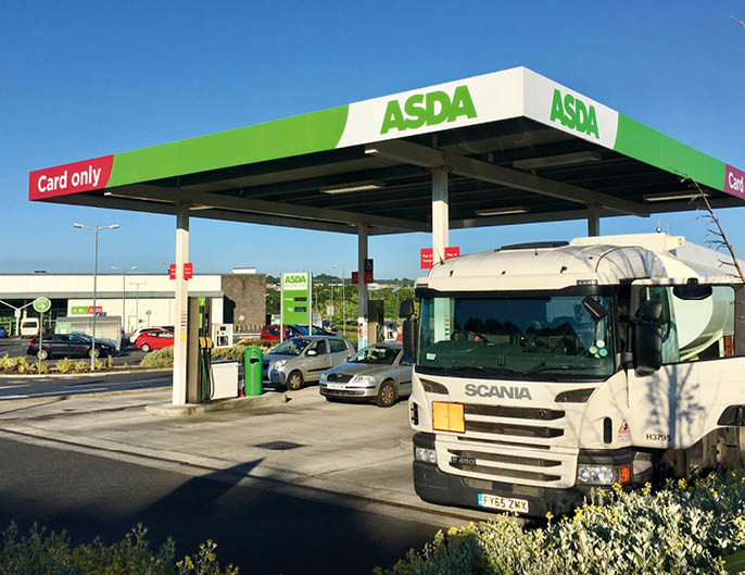 Gorseinon, UK: June 27, 2018: A self-service petrol station at an Asda supermarket  A Scania delivery truck is off-loading its fuel to the underground storage tanks  Asda is owned by Wal-mart 