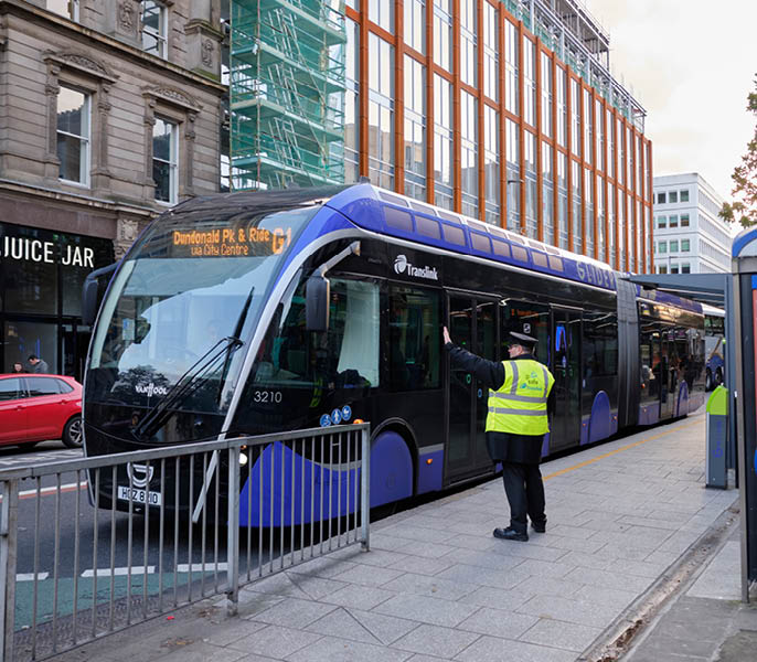 Glider transit, Van Hool ExquiCity 18 vehicle in centre of Belfast stop. Driver waiting for instruction from coordinator.  Belfast, UK,  October 3, 2019