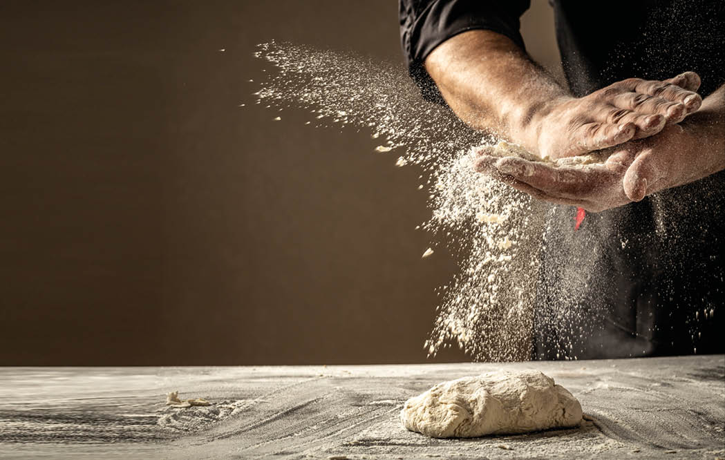 Photo of flour and men hands with flour splash  Cooking bread  Kneading the Dough  Isolated on dark background  Empty space for text 