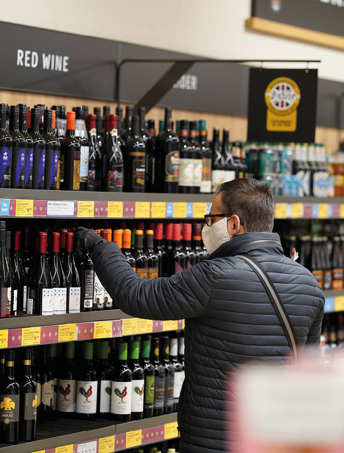 Thornbury, England-December 04, 2020: A man wearing a face mask is shopping for alcohol