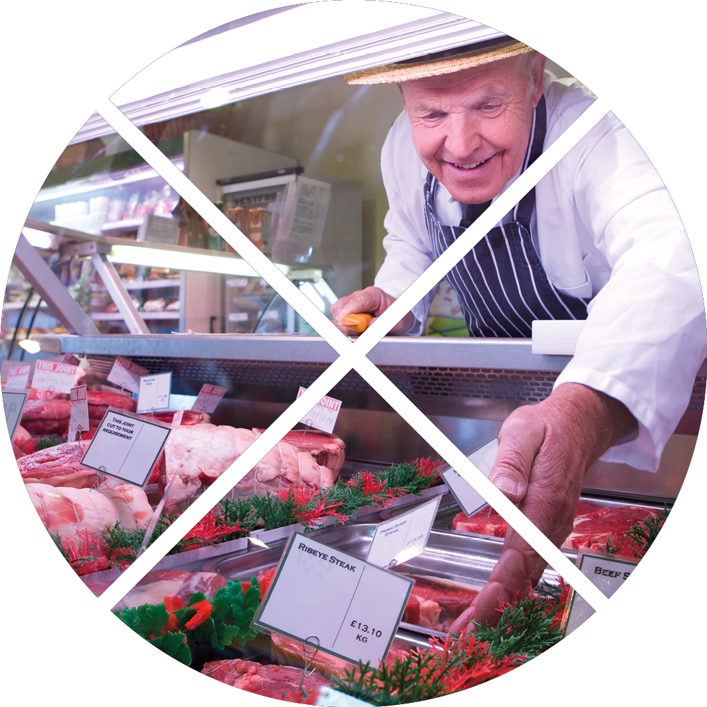 Butcher in apron and hat arranging display of meat in shop chiller