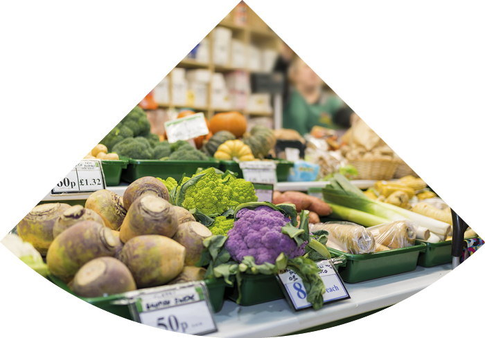 Close up of delicious and colourful vegetables with the market stall and market trader blurred in the background serving a client in England, UK
