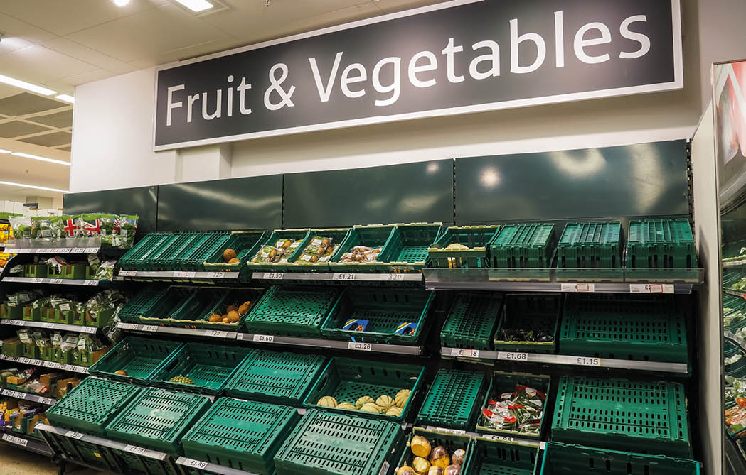 London, Bishopgate, UK  April 24th 2020: Tesco Bishopgate branch, showing low stocks of fruit and vegetables on shelves  Upturned green container baskets  London lockdown  Food shortage 