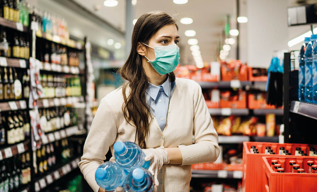 Woman with mask safely shopping for groceries amid the coronavirus pandemic in a stocked grocery store COVID-19 food buying in supermarket Panic buying,stockpiling Lockdown preparation Water shortage