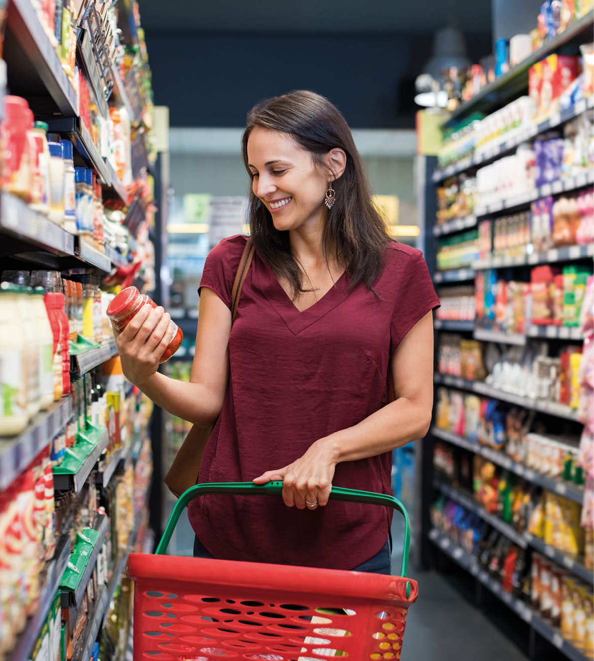 Happy mature woman looking at product at grocery store  Smiling hispanic woman shopping in supermarket and reading product information  Costumer buying food at the market 