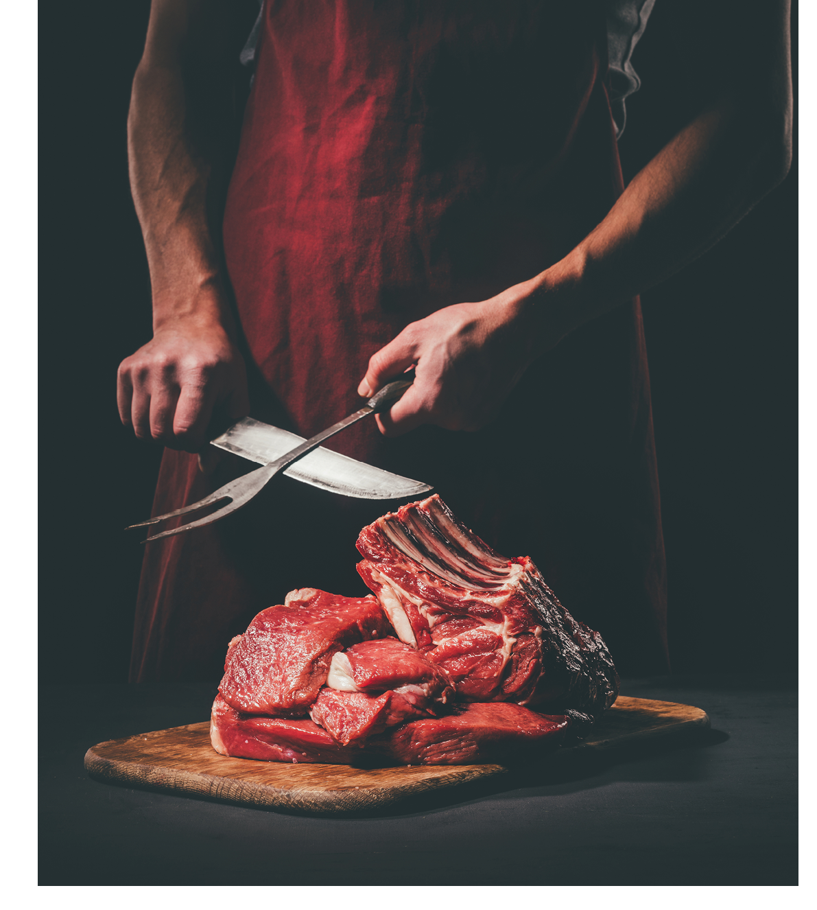 butcher sharpening knife to cut raw meat on wooden cutting board