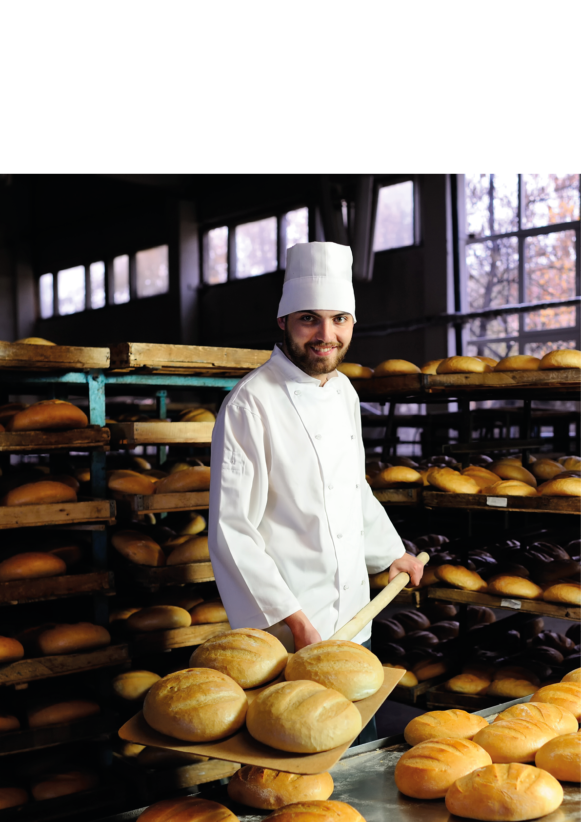 young cute baker smiling pulls out of the oven fresh bread shovel bread