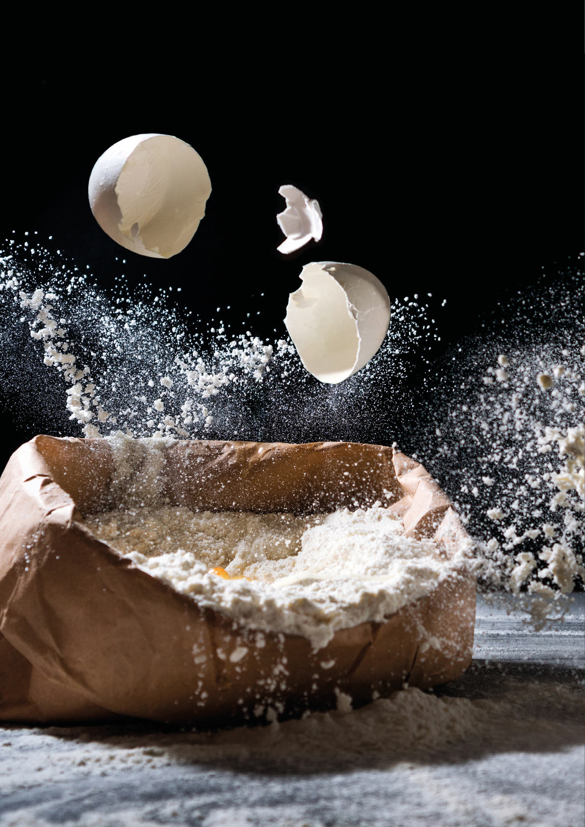 Bag with flour and egg flying in flour on black background  Flour splash  Cooking, baking concept