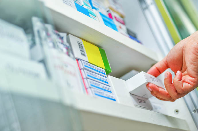 Closeup pharmacist hand holding medicine box in pharmacy drugstore 