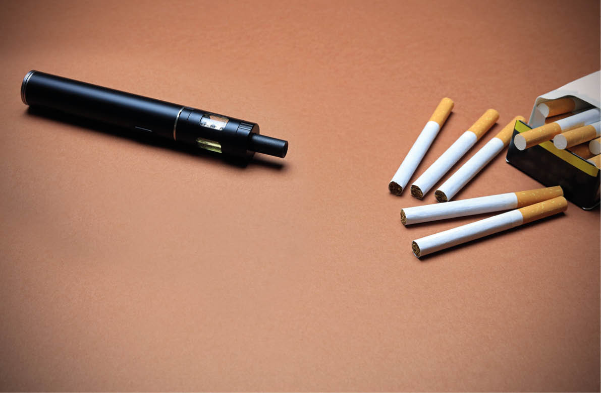 A Vape Pen And Cigarettes On A Brown Background. The Choices Between Vaping And Smoking.