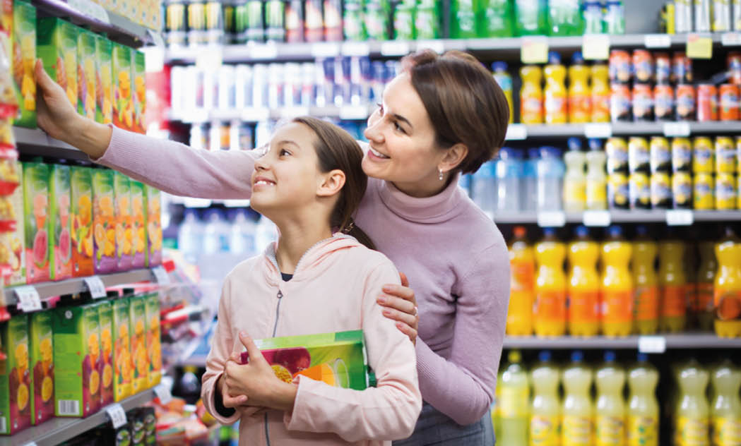 Glad female shopper with teenage daughter searching for beverages in supermarket