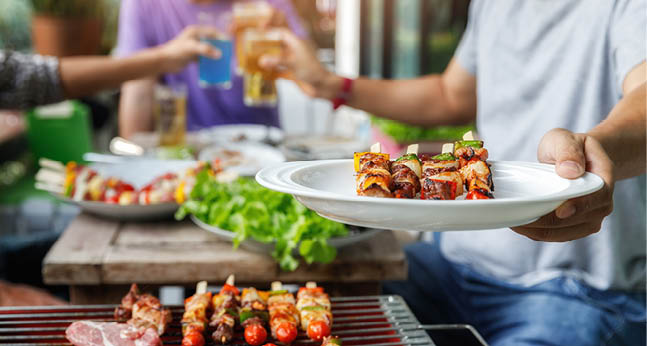 A man with a barbecue plate at a party between friends. Food, people and family time concept.