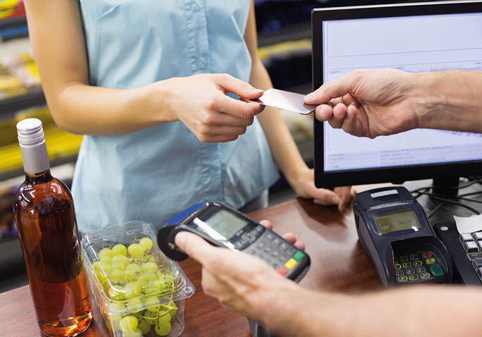 Woman at cash register paying with credit card in supermarket