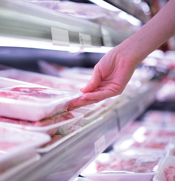 Woman's hand picking up packaged meat at the grocery store