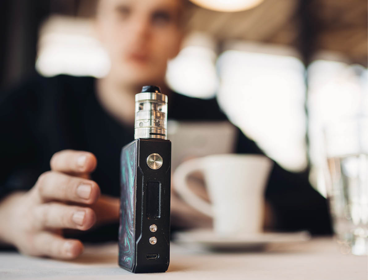 Using electronic cigarette to smoke in public places.Smoke restriction,smoking ban.Using vaping device with flavoured liquid.E-juice vaping new technology.Give up tobacco.Smoking habit,nicotine addict