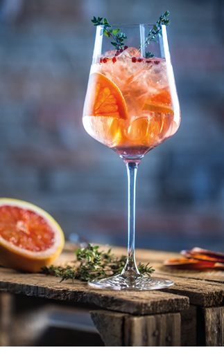 Cocktail drink on a old wooden board. Alcoholic beverage with tropical fruits red pepper herb and ice.