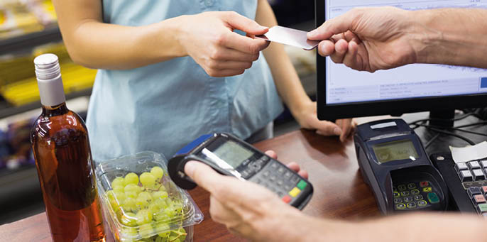 Woman at cash register paying with credit card in supermarket