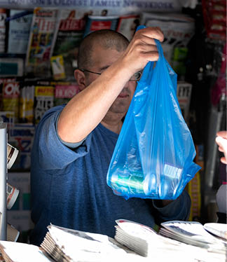 London, UK - September 13, 2018: Chelsea street with closeup vendor man selling plastic bag with drinks in dailymail daily mail newsstand newspaper magazine stand news