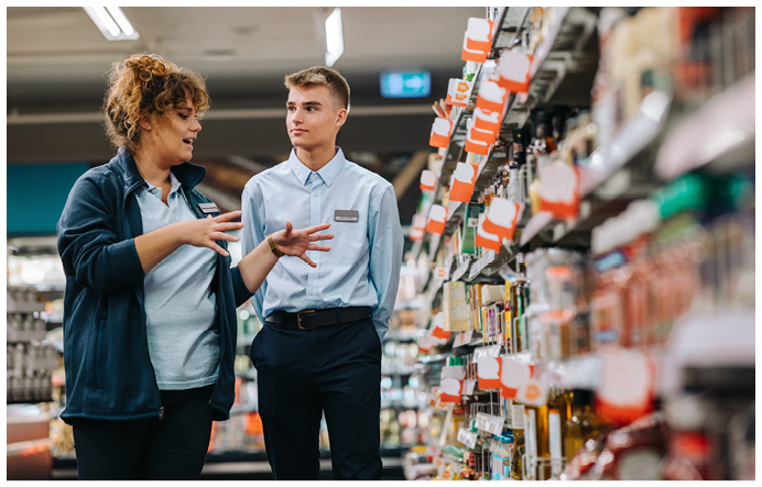 Store manager training young worker. Supermarket manager giving training to a trainee.