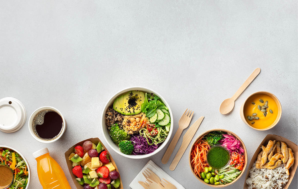 Healthy take away food and drinks in disposable eco friendly paper containers on gray background, top view. Fresh salad, soup, poke bowl, buddha bowl, fruits, coffee and juice.