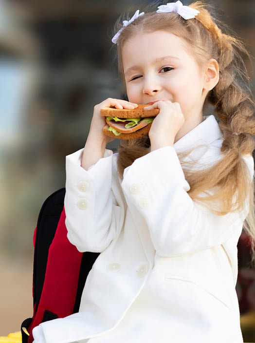 cute little girl eating sandwich during break between classes. healthy unhealthy food for kid. breakfast lunch for children at school. copy space, text