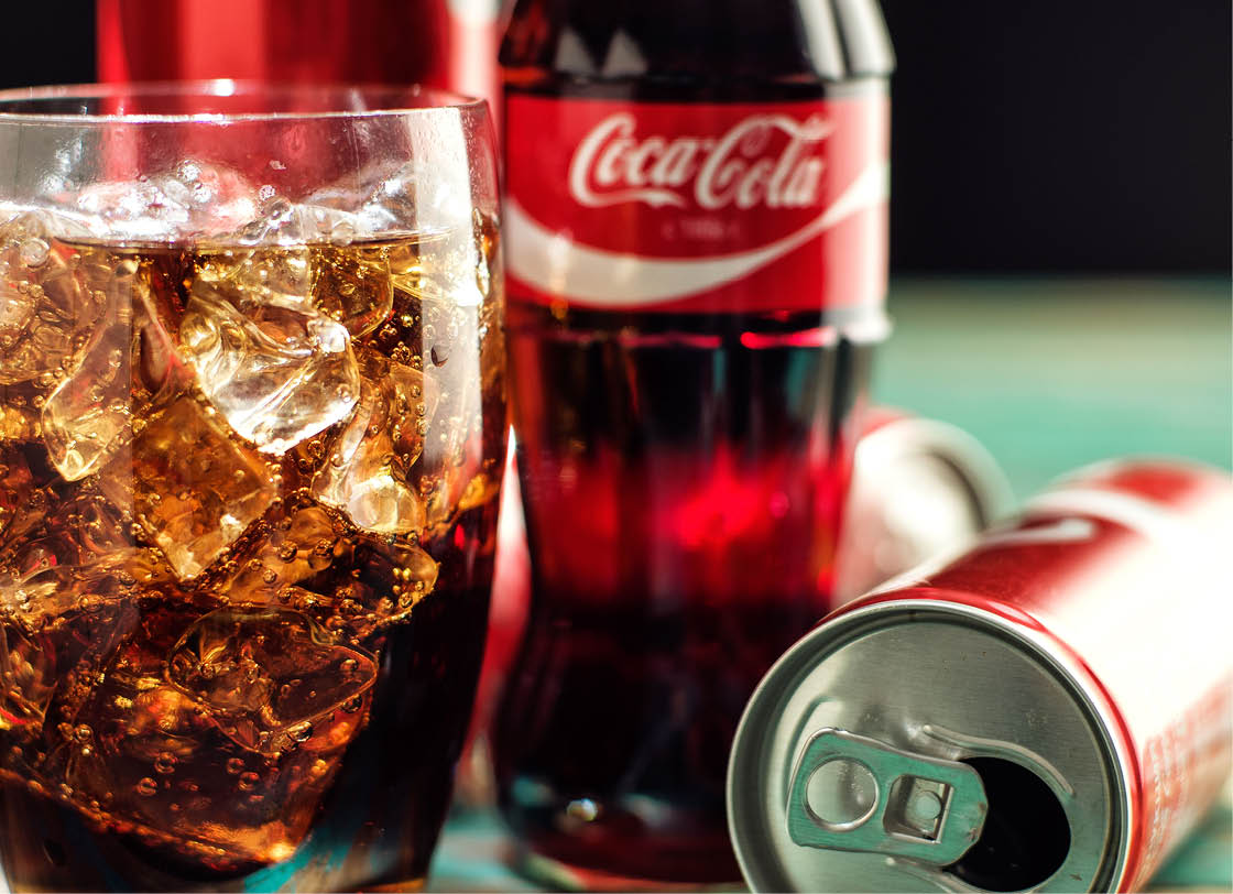 MINSK, BELARUS-AUGUST 26, 2016: Glass of Coca-Cola with ice, can and bottle of Coca-Cola on wooden background  Coca-Cola is a carbonated soft drink sold in stores, throughout the world 