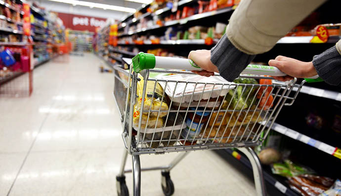 London, UK - August 18, 2014: A shopper pushes a trolley along an aisle in an Asda supermarket  American company Walmart owns Asda, which is UK's largest retail chain after Tesco with 568 stores 
