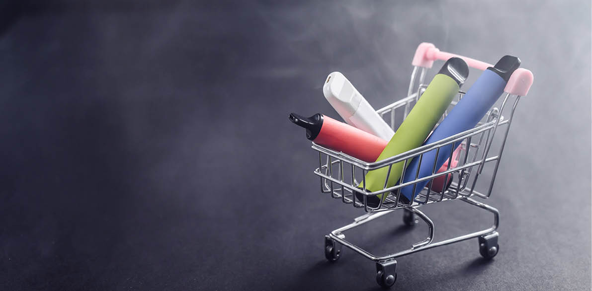 Disposable vapes in a shopping cart on a black background. Modern electronic cigarettes.
