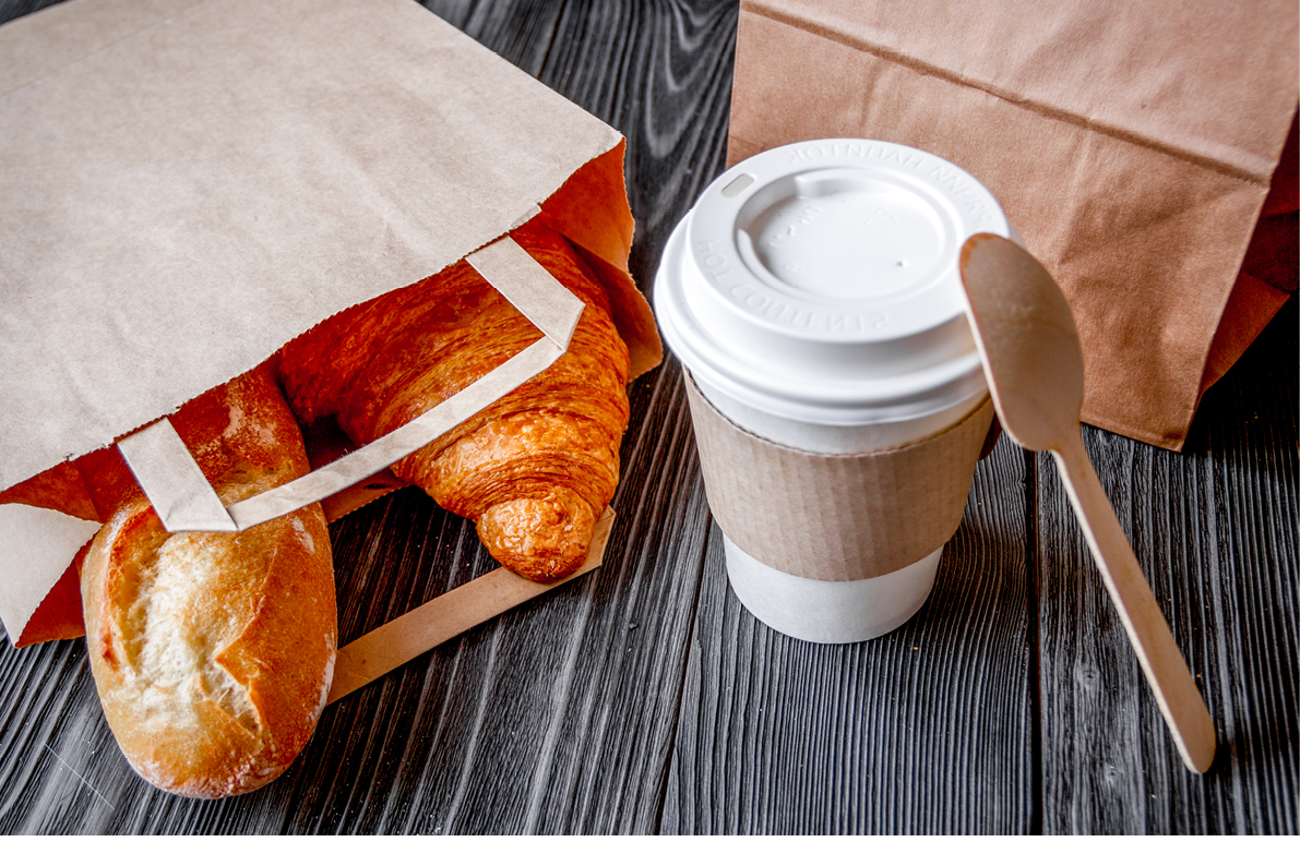 cup coffee and croissant in paper bag on wooden background