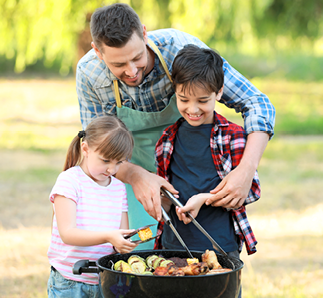Little children with father cooking tasty food on barbecue grill outdoors