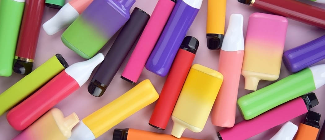 Set of multicolor disposable electronic cigarettes on a pink background. The concept of modern smoking, vaping and nicotine.