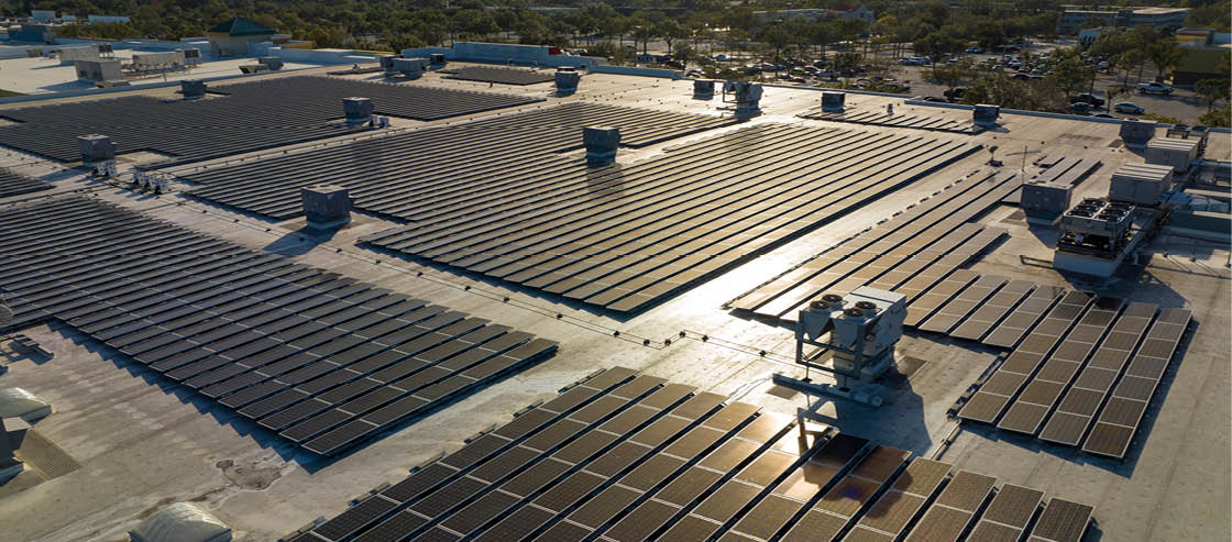 Aerial view of blue photovoltaic solar panels mounted on industrial building roof for producing green ecological electricity. Production of sustainable energy concept