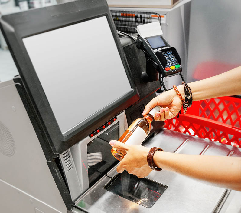 Girl customer scans bottle of wine at the self-service checkout in the grocery supermarket shop