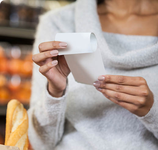 Mid section of woman holding bill in grocery section of supermarket