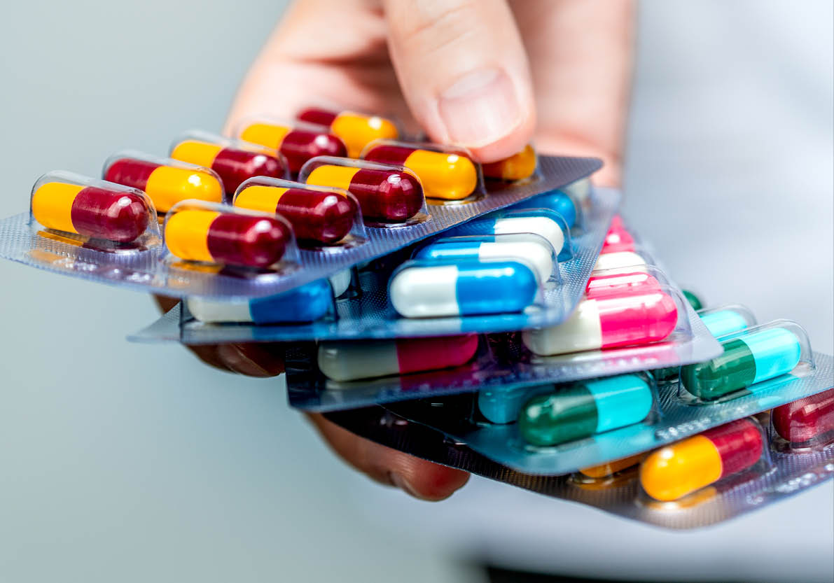 Pharmacist or doctor hand holding pack of antibiotic capsule pills and giving patient or people. Antibiotic drug overuse. Antimicrobial drug resistance. Community pharmacist. Drugstore background.