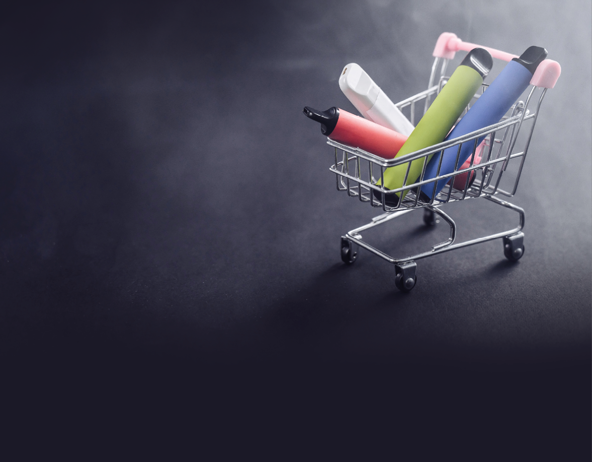 Disposable vapes in a shopping cart on a black background. Modern electronic cigarettes.
