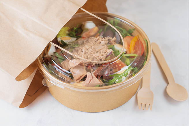 Fish diet salad with tuna, tomatoes, arugula on light background. Healthy vegetarian lunch. Concept eco restaurant delivery, environment protection. Take away food in brown paper craft plate. 