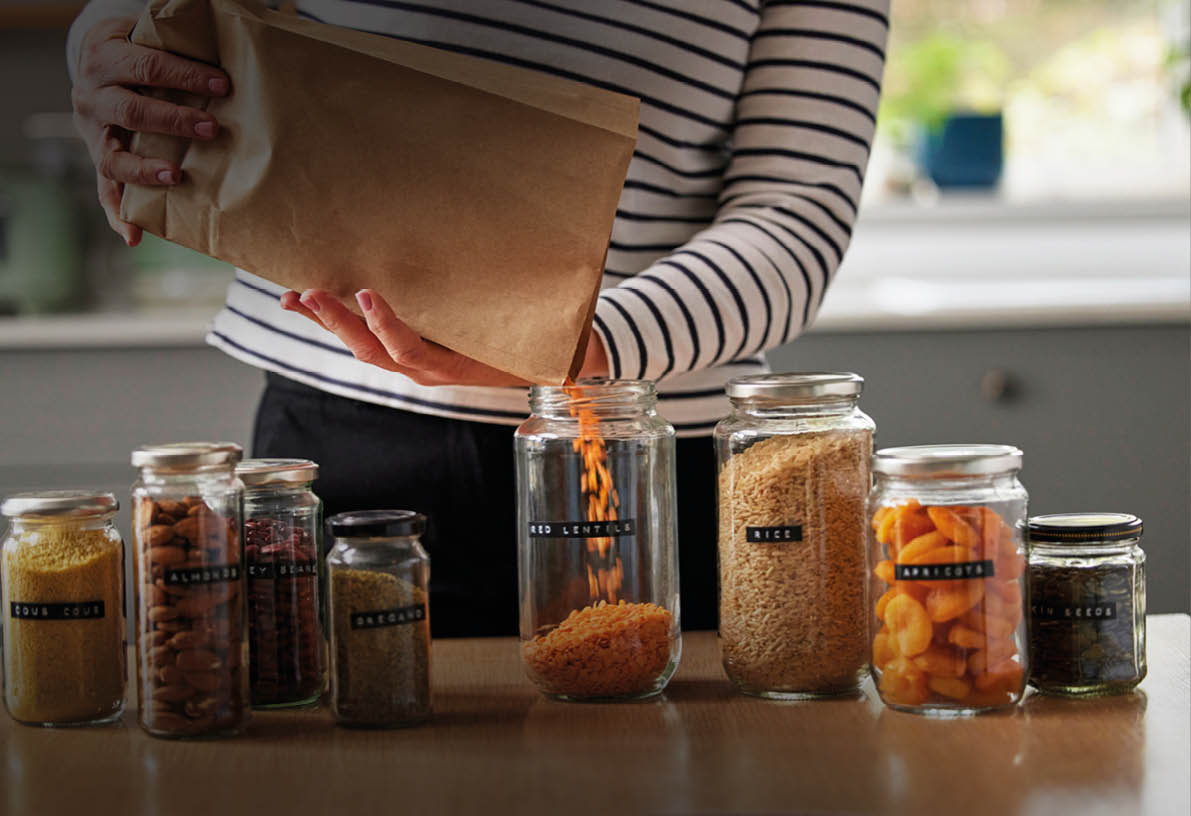 Woman Saving On Packaging By Filling Recycled Jars To Store Dried Food At Home