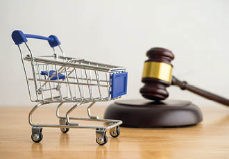 Shopping trolley cart and hammer judge gavel on wooden table with white wall background copy space. Consumer rights and and responsibilities to safety, customer protection, commercial law concept.