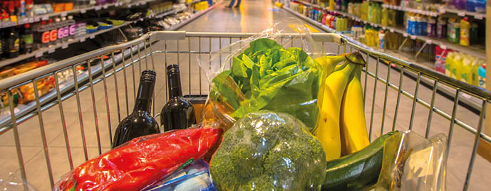 Supermarket trolley at an aisle filled up with healthy vegetables seen from the consumers point of view from above