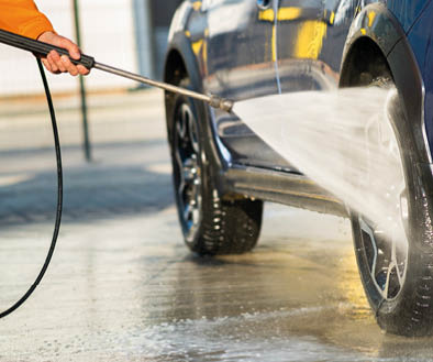 Closeup of male driver washing his car with contactless high pressure water jet in self service car wash.