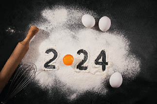 Creative Happy New Year 2024 greeting card for home baker. Numbers made out of flour with egg yolk, Christmas baking concept, top view