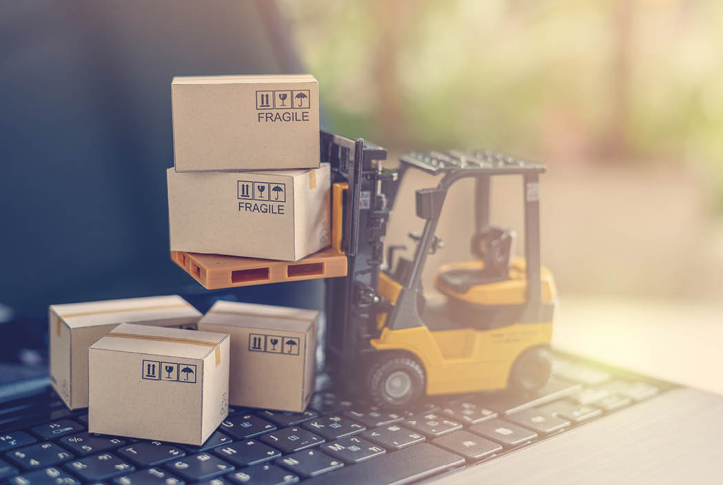 Logistics, supply chain and delivery service concept : Fork-lift truck moves a pallet with box carton. Boxes on a laptop computer, depicts wide spread of products around globe in ecommerce booming era